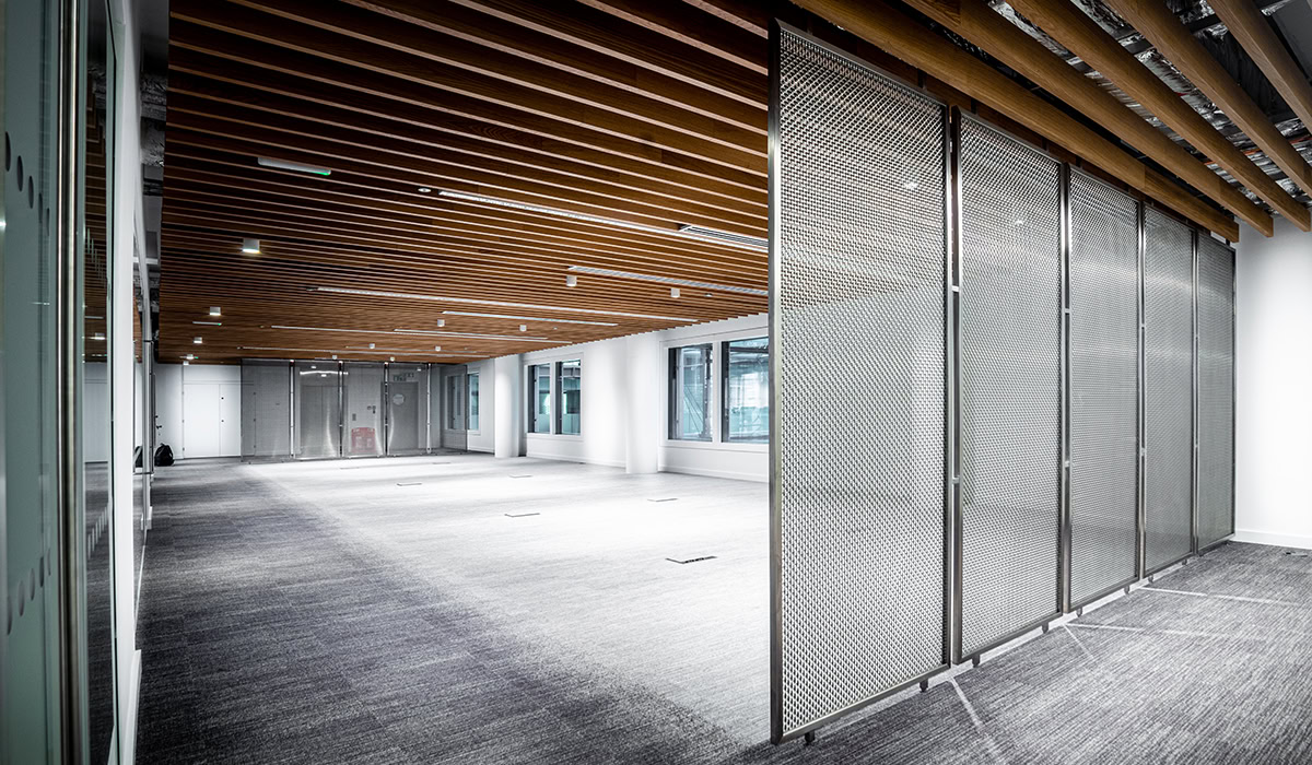 Metal mesh partition wall system in a commercial interior with exposed ceiling beams