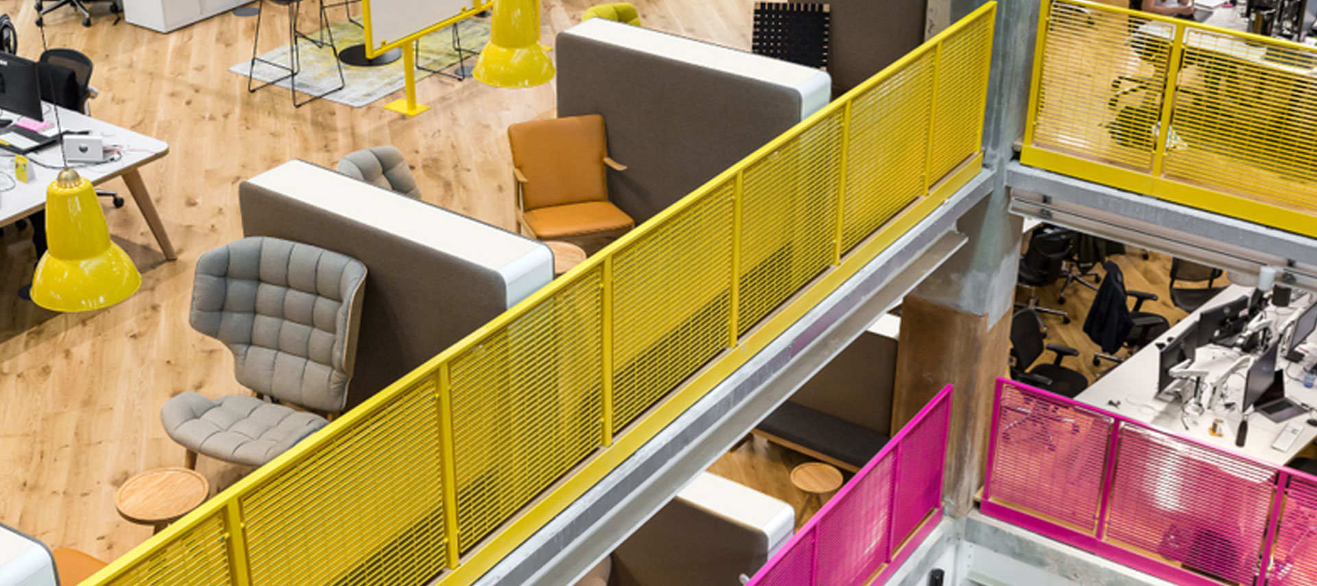 Multi-level office interior with yellow metal balustrades and open workspace design