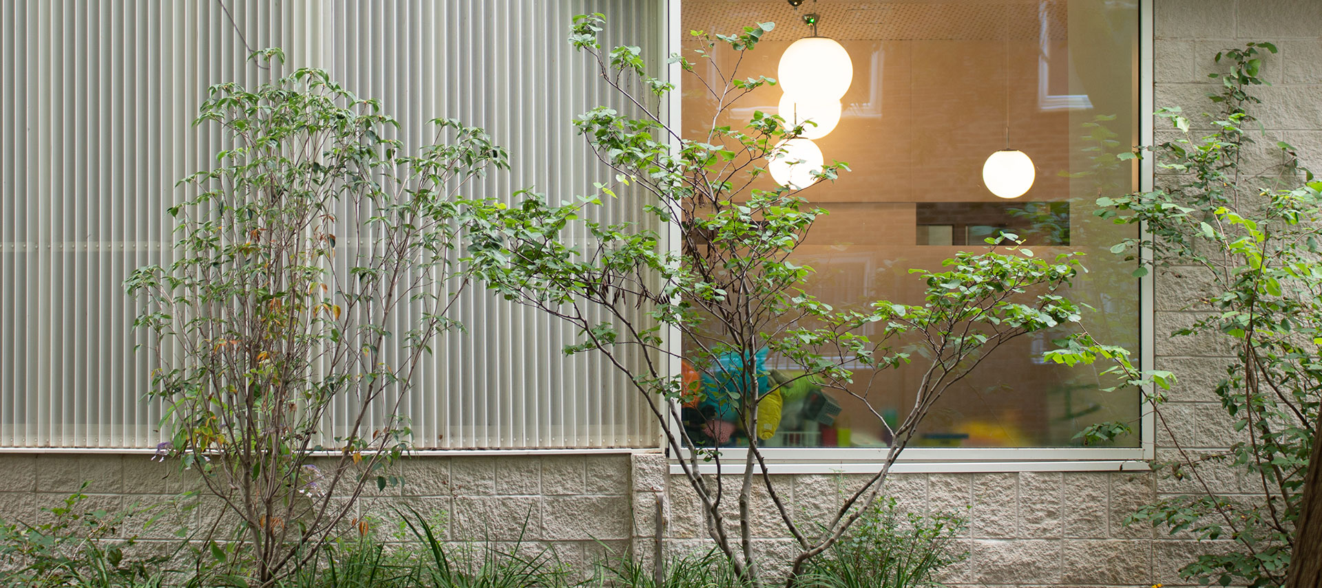 Exterior view of modern building with metal mesh façade and landscaped surroundings