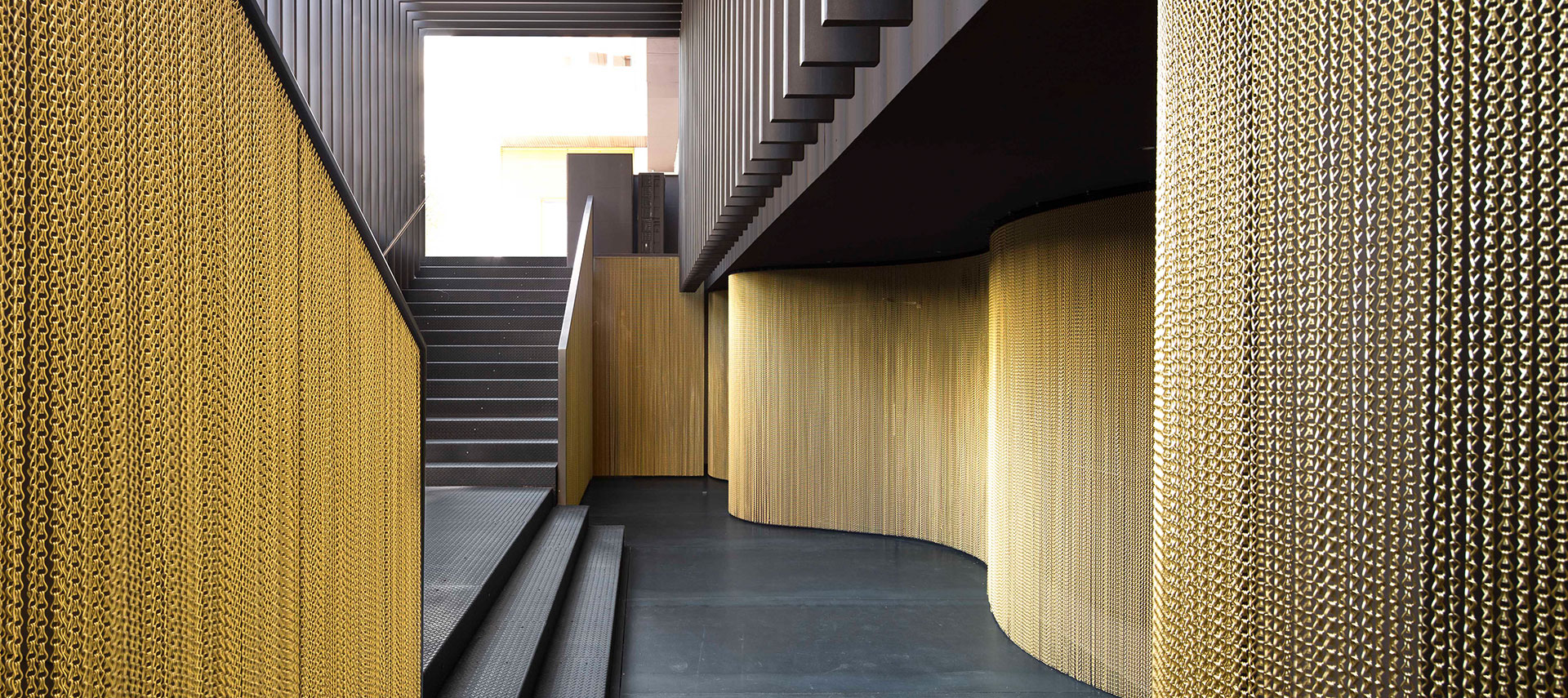 Bespoke metal mesh wall cladding in a contemporary commercial interior corridor