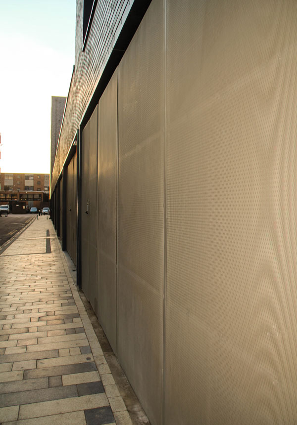 Close-up of perforated metal sheet cladding panels with door integration.