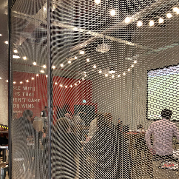 Expanded mesh partition wall in hospitality venue