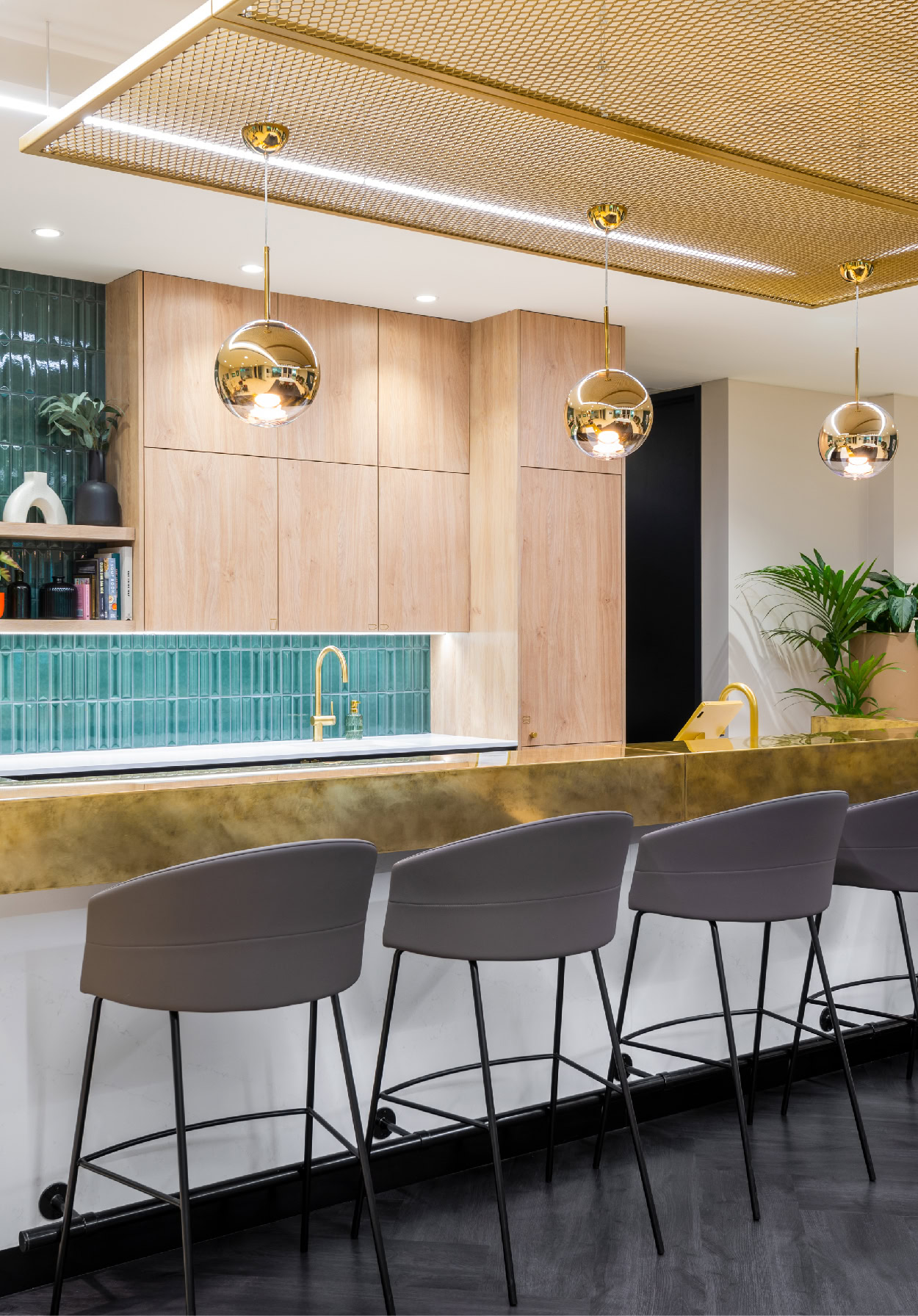 A gold mesh ceiling over a white and gold bar, with grey high stools