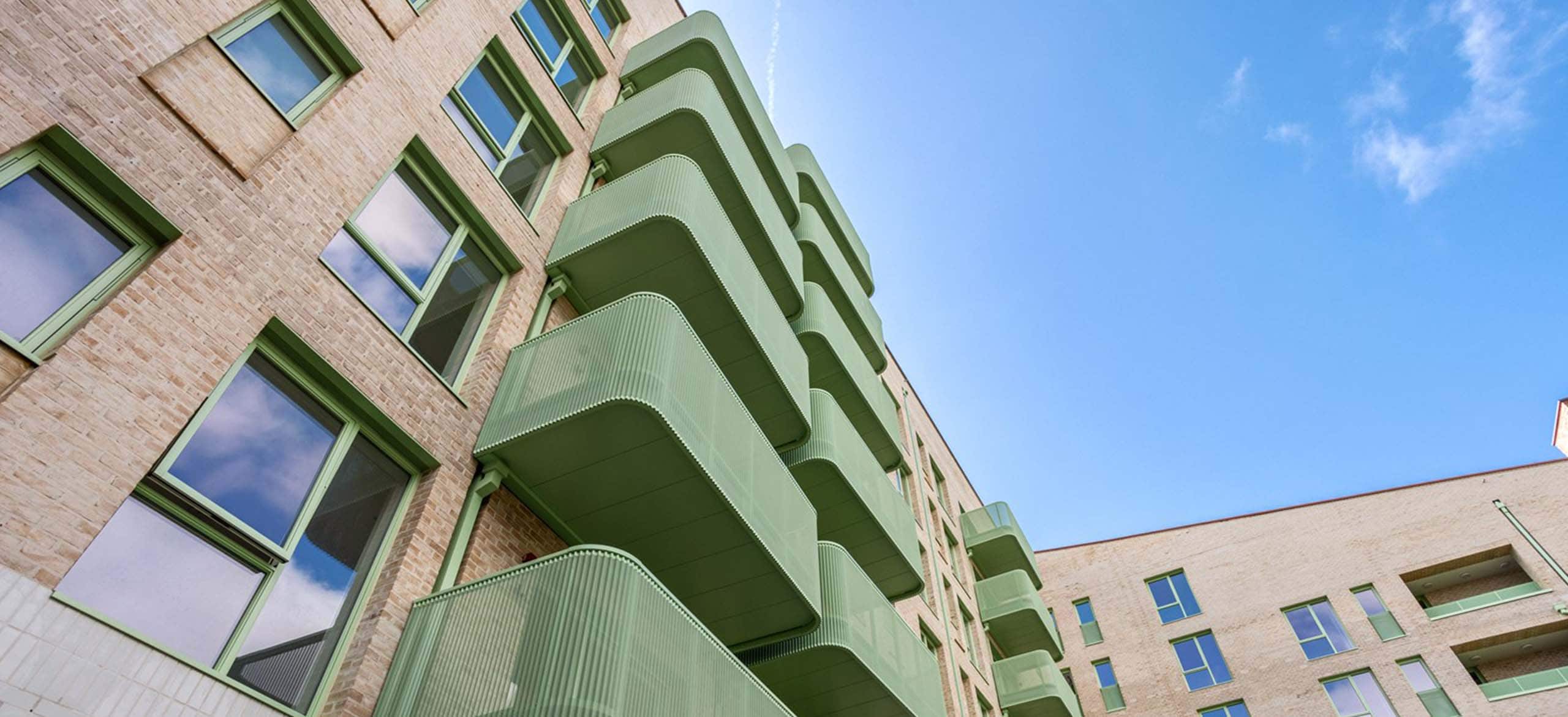 A photo from below a tall residential building with wellTEC profiled sheet balcony.