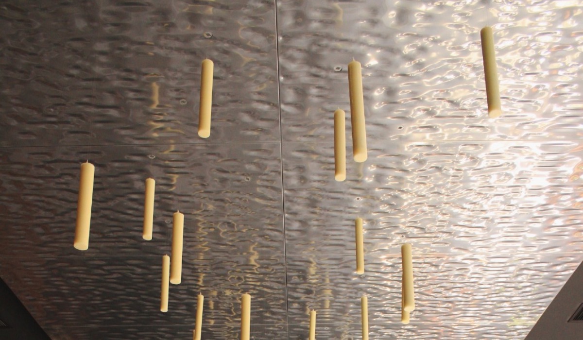 A silver reflective ceiling with candle sticks suspended from it