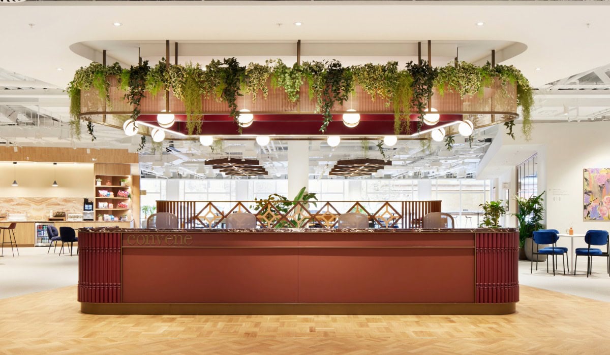A copper bar area, with a woven mesh gantry that has greenery draped over it and circular lights hanging from it