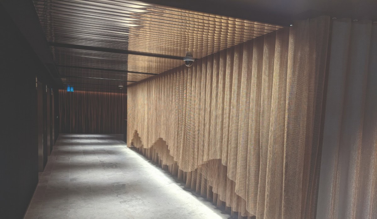 An empty corridor with a decorative bronze Alpha Mesh wall covering