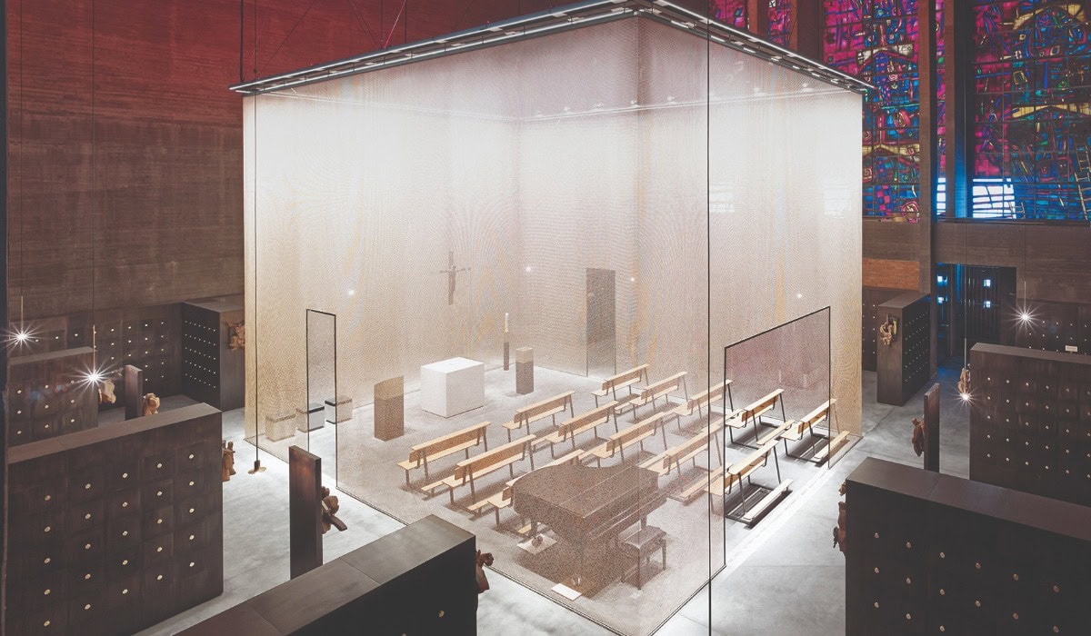 A large grey Alpha mesh cube creating a defined space for worship with seats