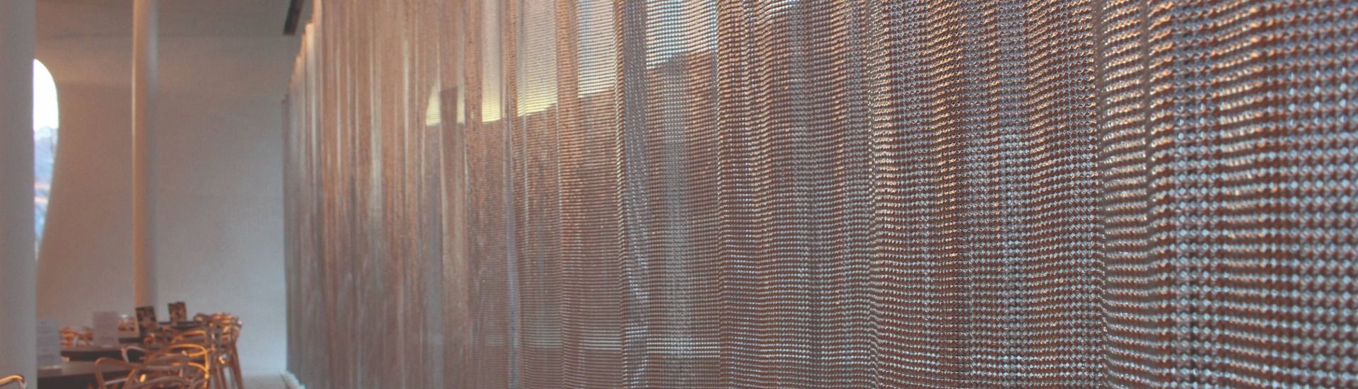 Alpha-Mesh A stainless steel metal curtain against a window