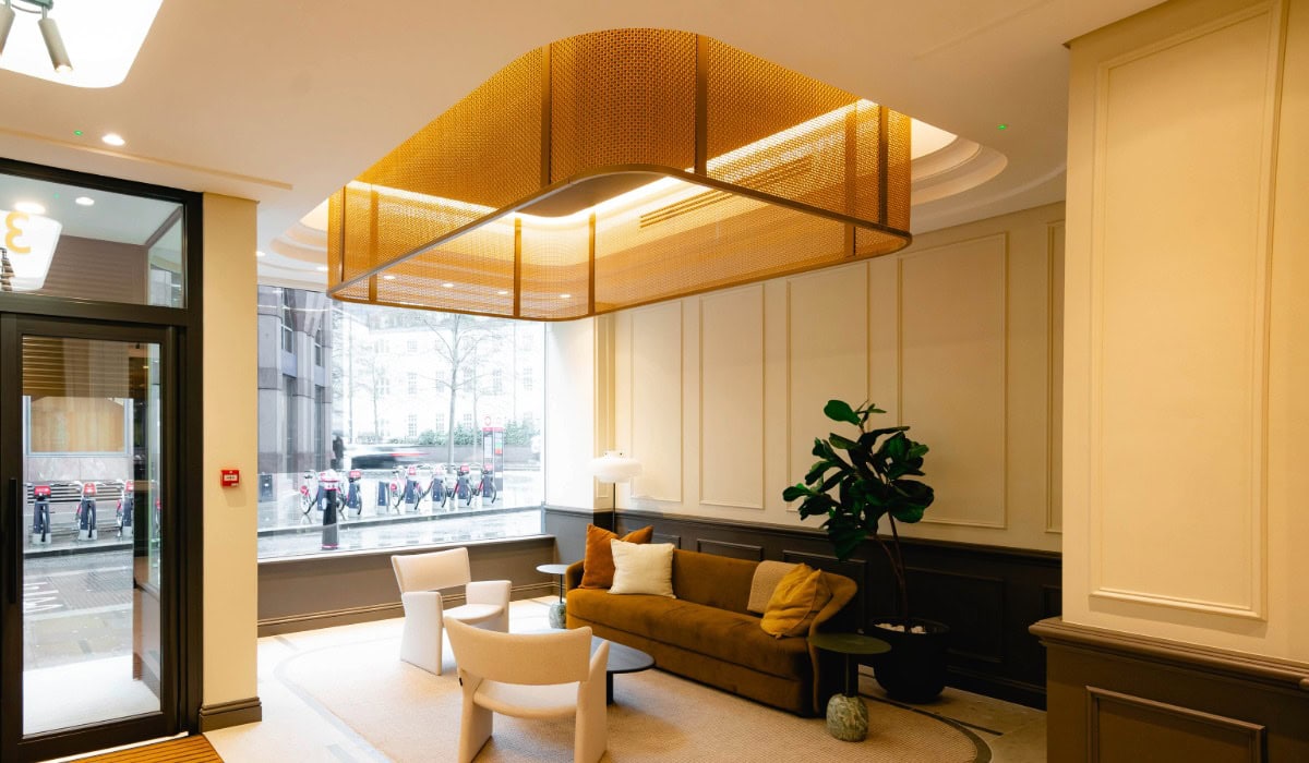 A pale yellow reception lobby with a deep gold mesh gantry lit by led strip lighting