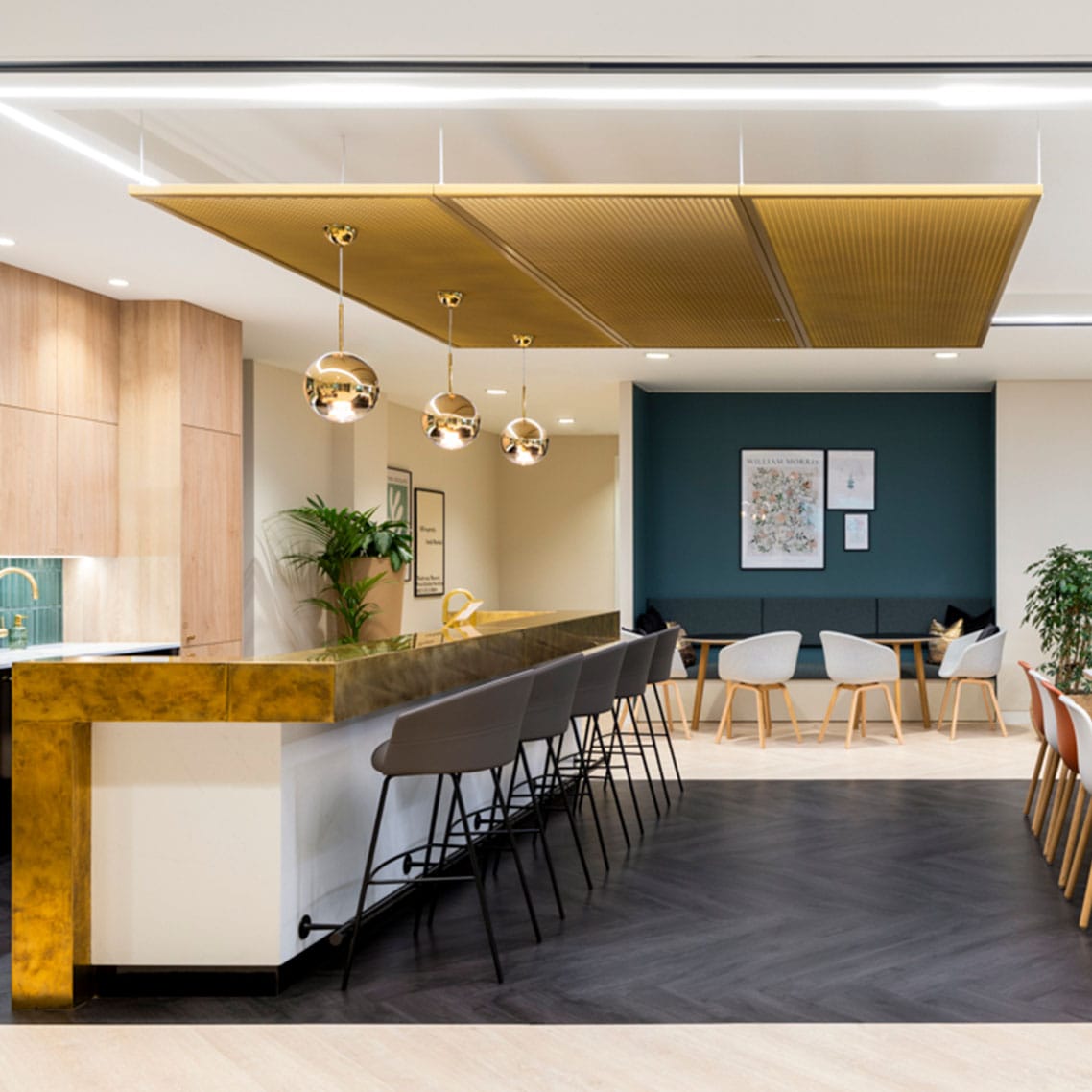 A seating are with a bar top in an office kitchen with a metal mesh AC400 ceiling system suspened above.