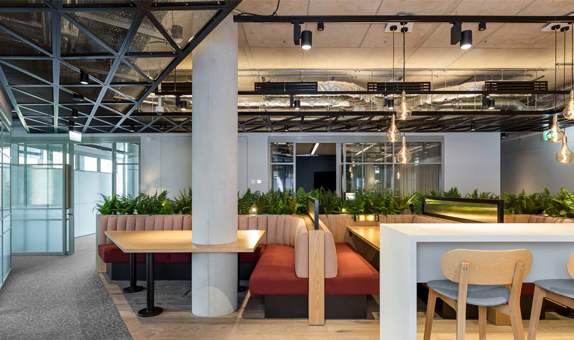 A large room with a seating area and a black metal mesh ceiling system above.