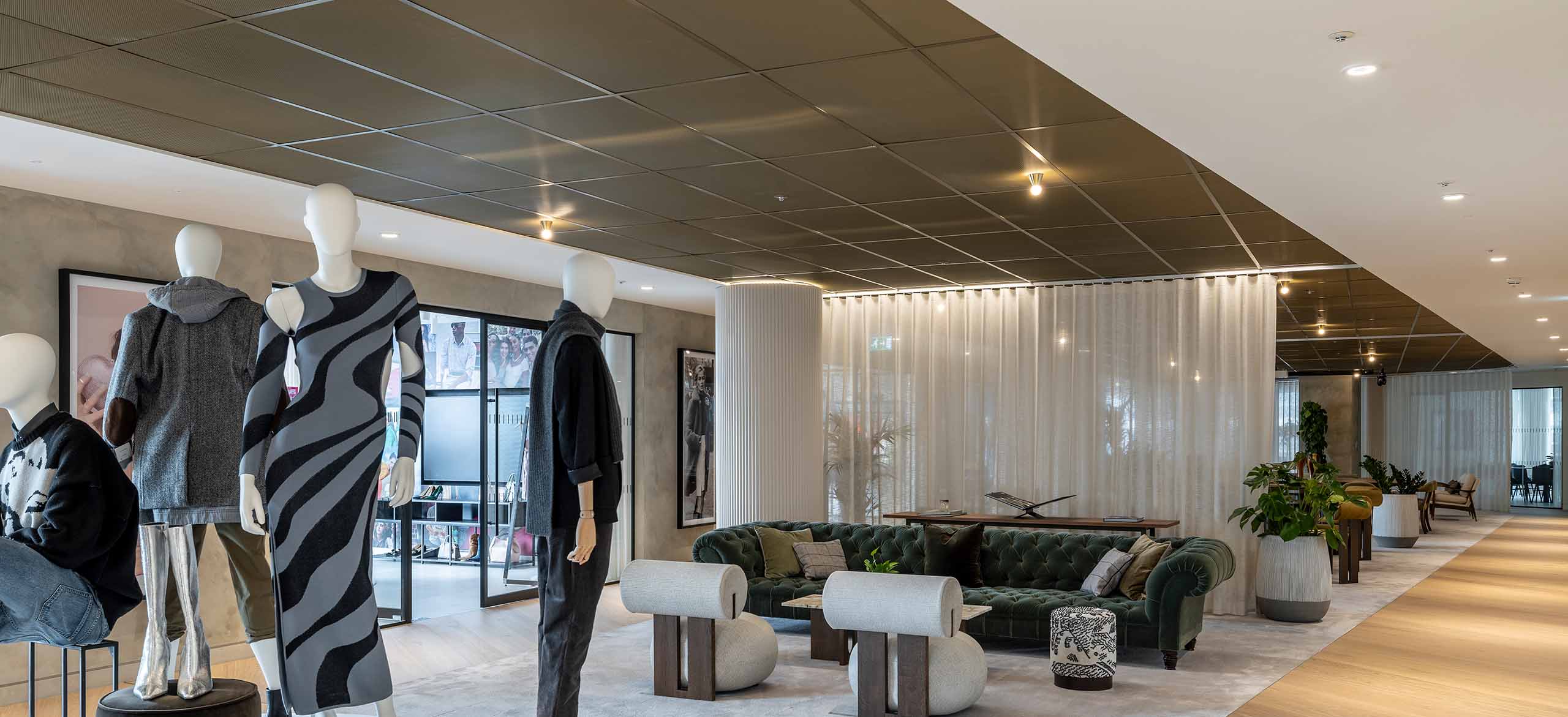 An image of a building with mannequins in and a large sofa. With a black expanded mesh ceiling system.