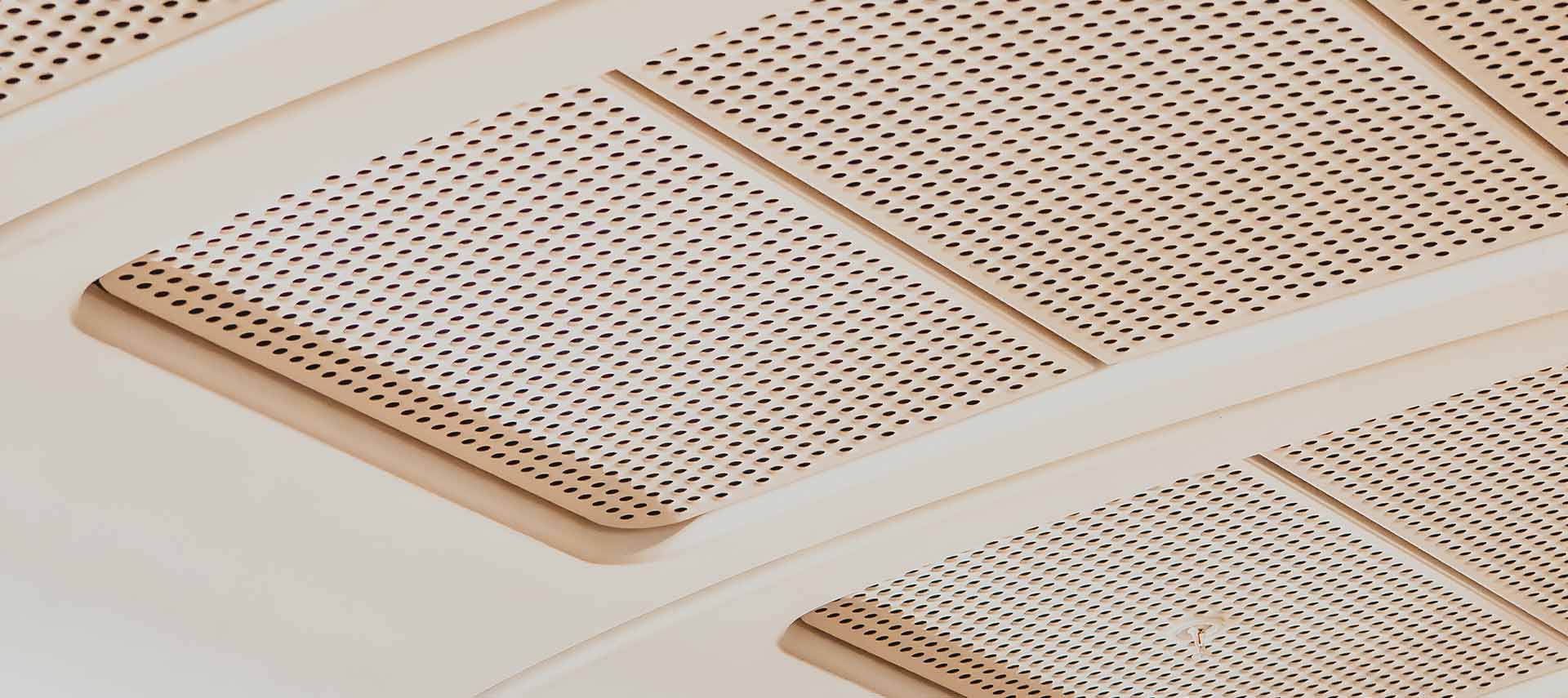 A close up image of a white perforated metal mesh ceiling system.