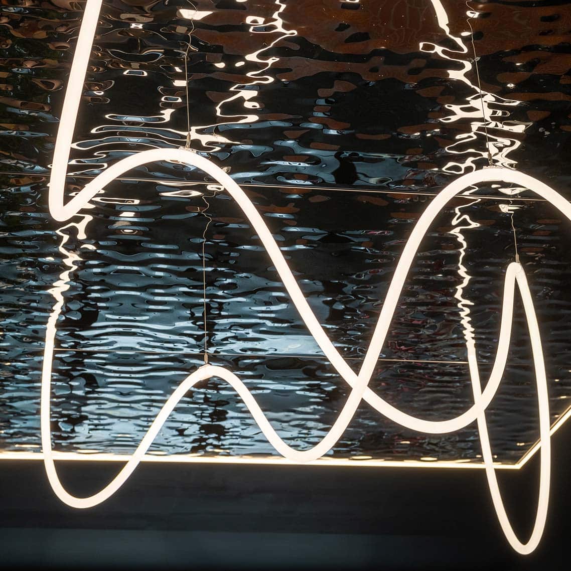 A Water ripple embossed ceiling reflecting the light from the suspended lighting, which is a swirly pattern.