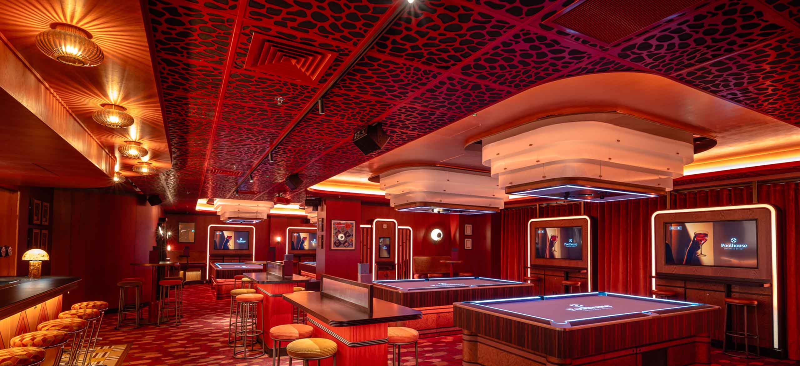 A games room in a bar venue. A red room with an AC100 bespoke laser cut metal ceiling system. Red furniture and a whole red theme running through the room.